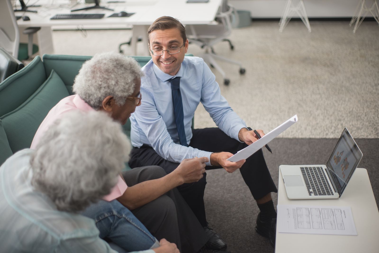An advisor going over travel plans with an older couple on a sofa