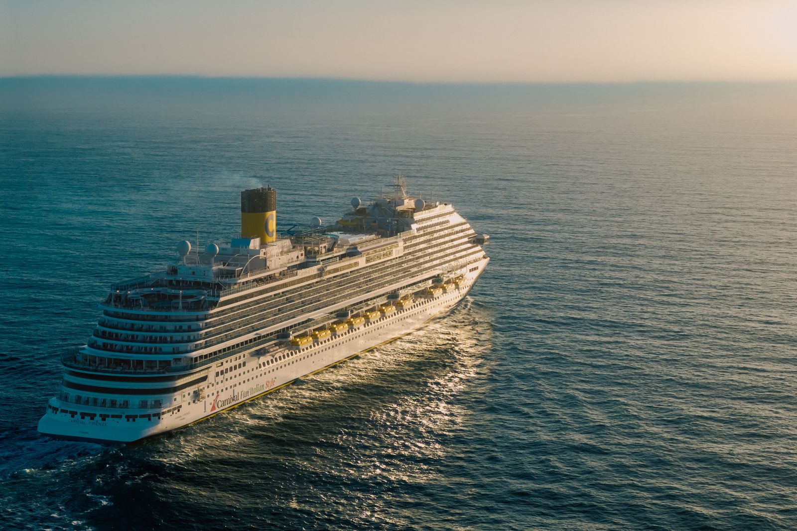 A cruise ship crossing open water as the sun sets