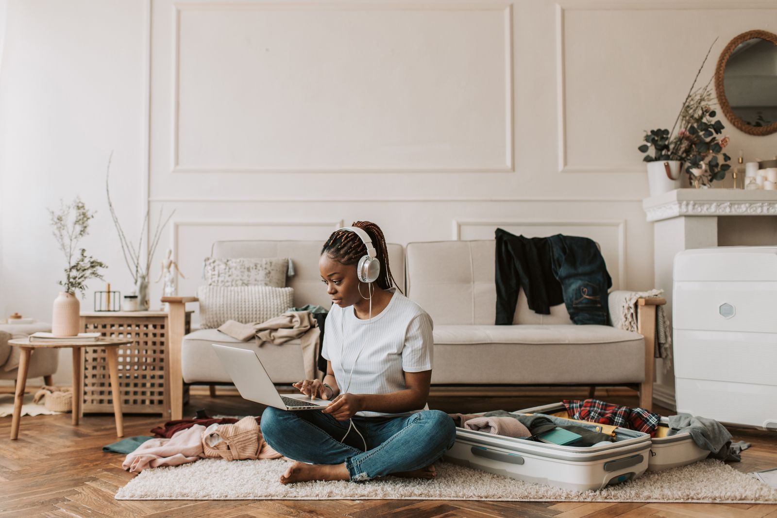 Woman at a laptop in her living room with a suitcase nearby