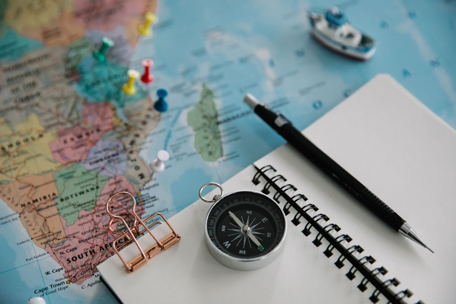 Map with pushpins beside a notebook and compass