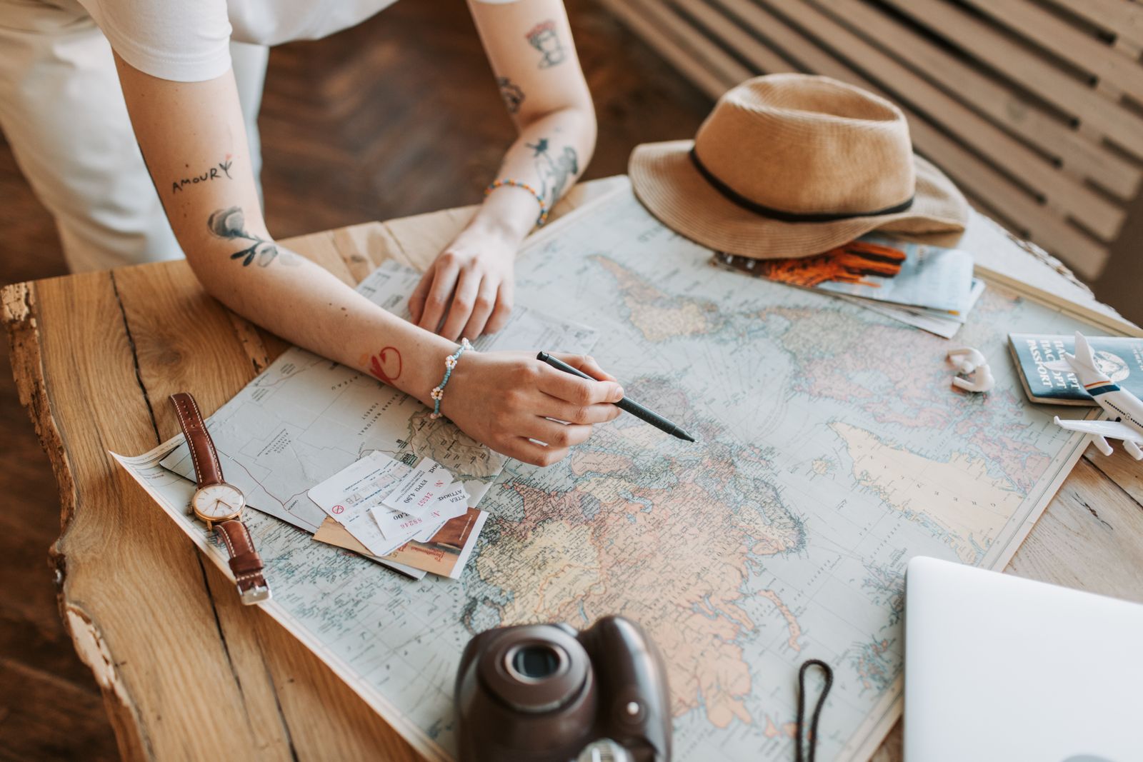 Hands planning a trip over a world map with a passport and camera